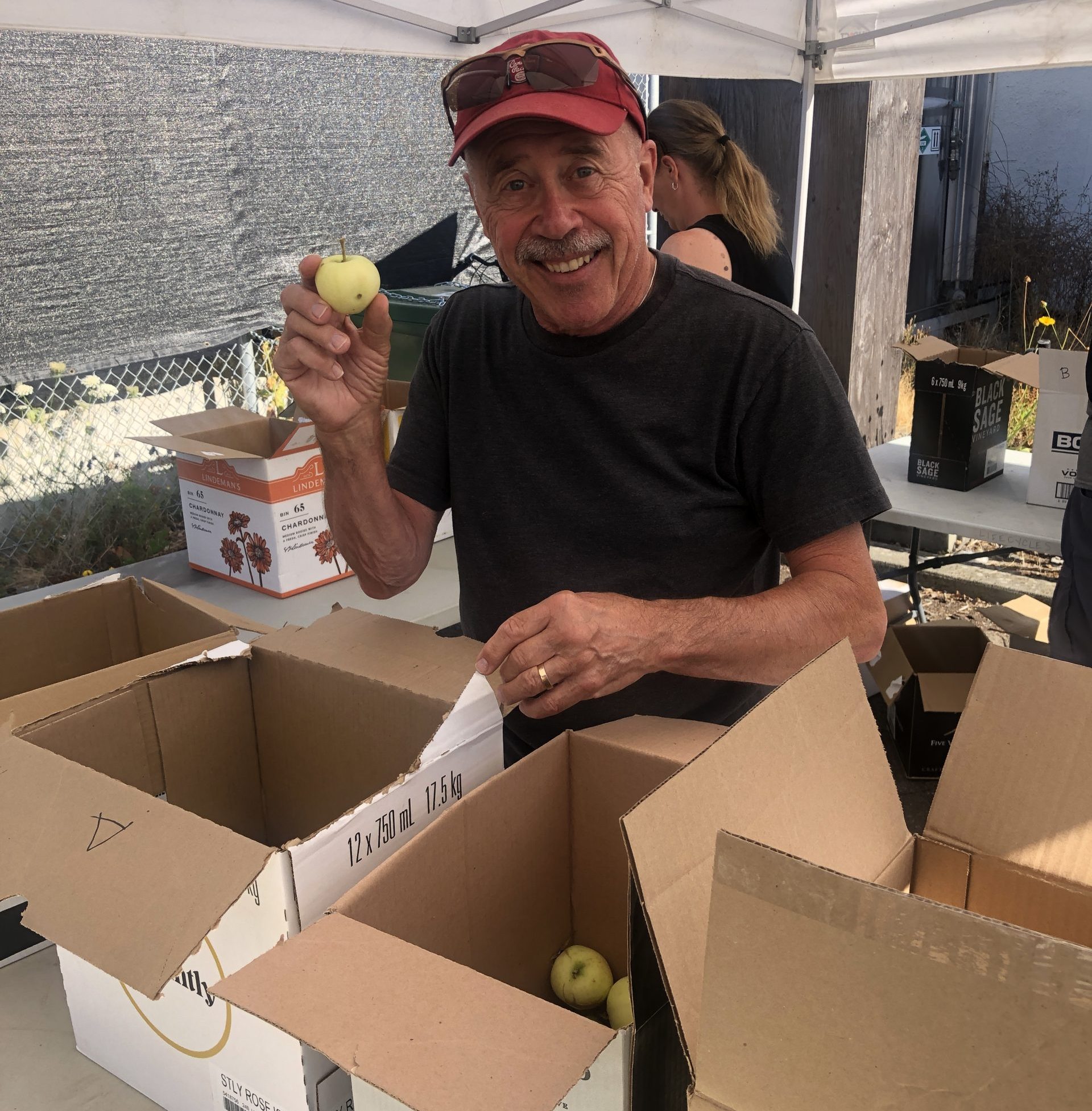 A LifeCycles volunteer holding up an apple while sorting fruit.